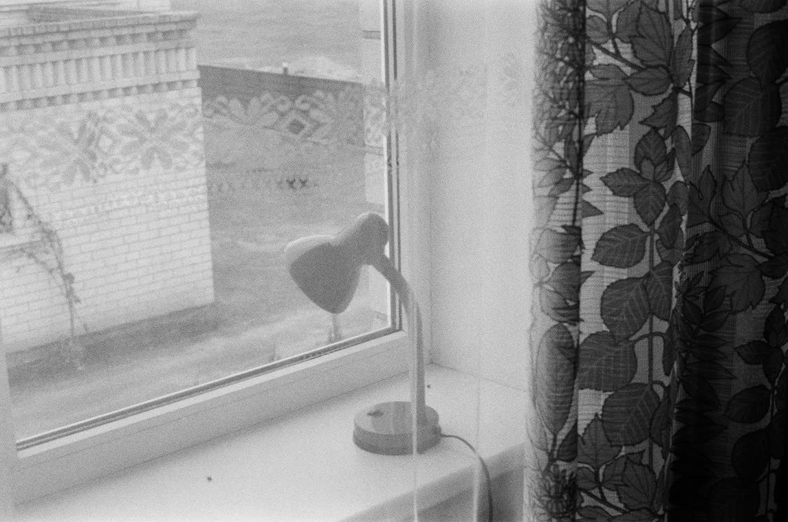 Lamp on a window sill behind a patterned curtain, 35mm